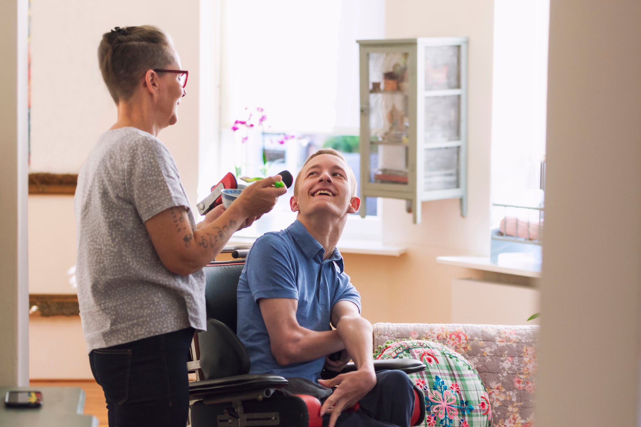 Person in a wheelchair interacting with another person in a home setting.